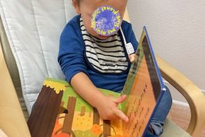 A toddler boy is reading a book.